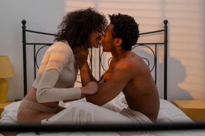 African-American couple in bed kissing