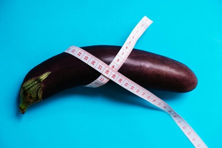 measuring tape wrapped around an eggplant on a blue background