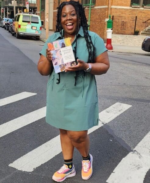 Mecca Woods posing with one of her books 