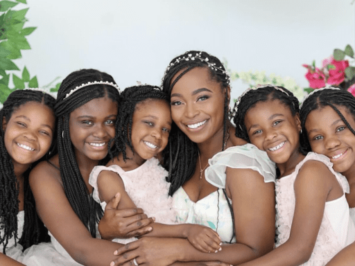 Black woman and five young girls smiling at the camera.
