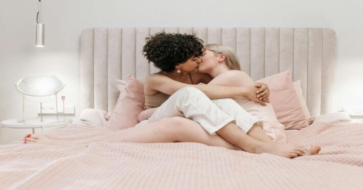 Lesbian couple kissing and hugged up in bed