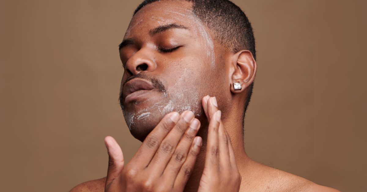 A close up of a man putting moisturizer on his face with his hands