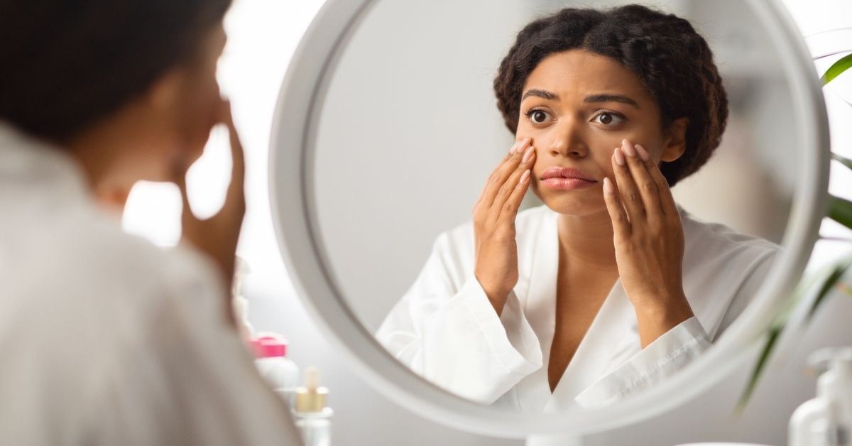 Woman with dull skin looking in mirror